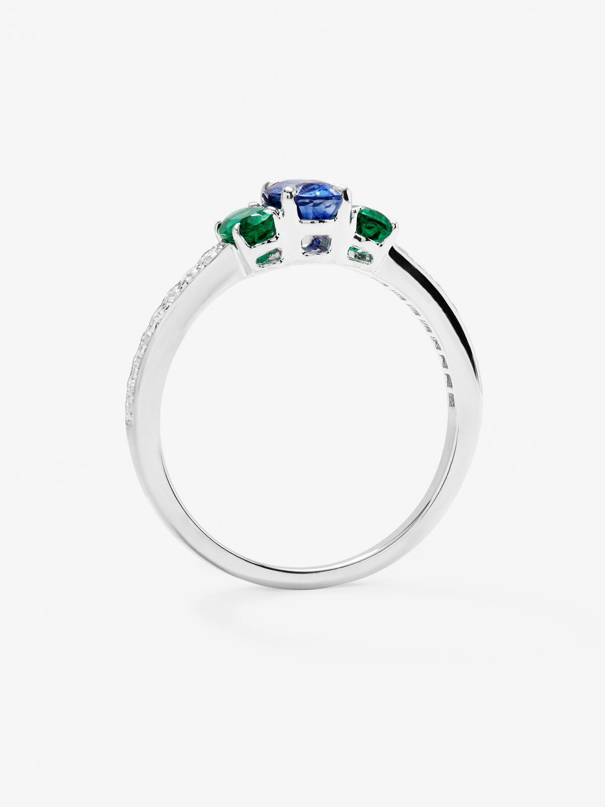 Anillo tresillo de oro blanco de 18K con zafiro azul en talla oval de 0,71 cts, 2 esmeraldas verdes en talla oval con un total de 0,5 cts y 10 diamantes en talla brillante con un total de 0,115 cts