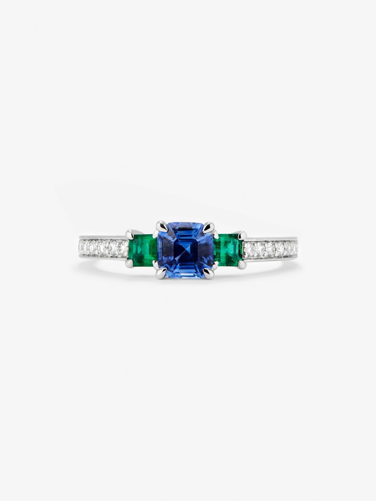 Anillo tresillo de oro blanco de 18K con zafiro azul en talla esmeralda de 0,71 cts, esmeraldas verdes en talla octogonal de 0,21 cts y diamantes blancos en talla brillante de 0,02 cts