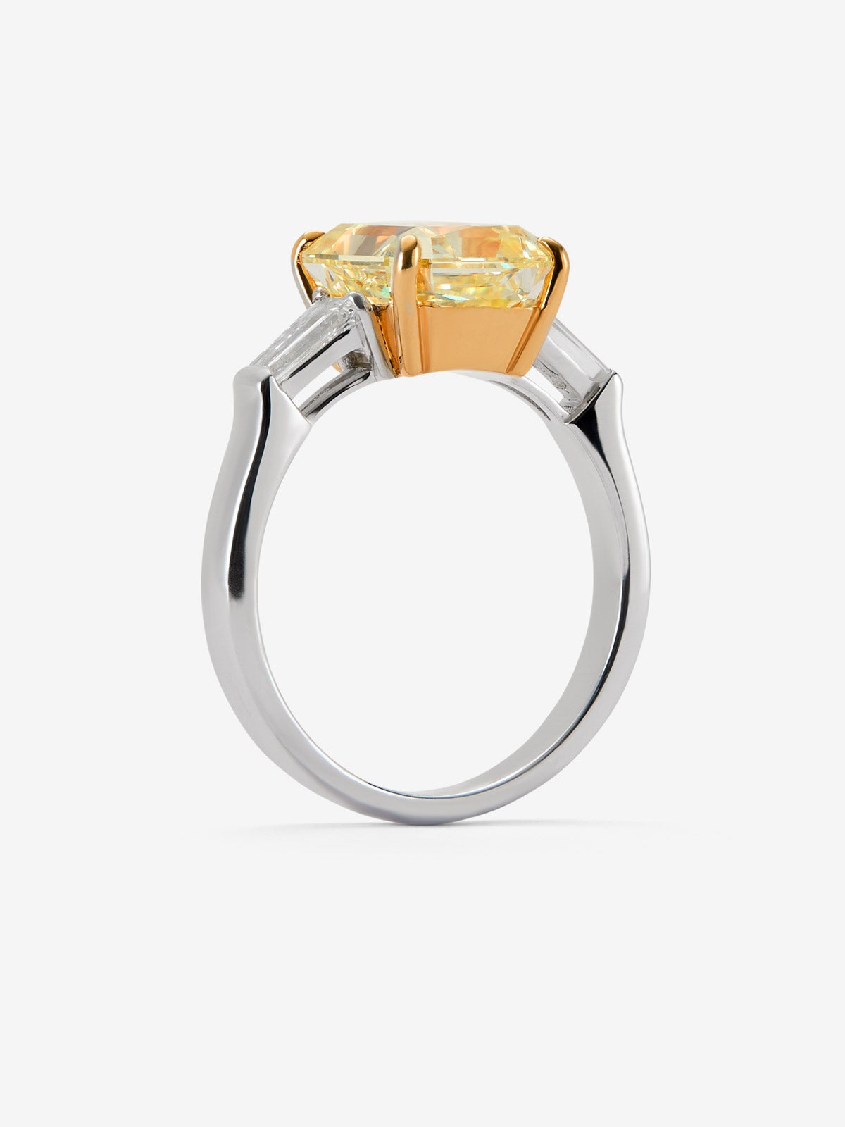 Anillo solitario de oro blanco de 18K con diamante Fancy Yellow en talla esmeralda de 4 cts y 2 diamantes talla trapecio con un total de 0,4 cts 