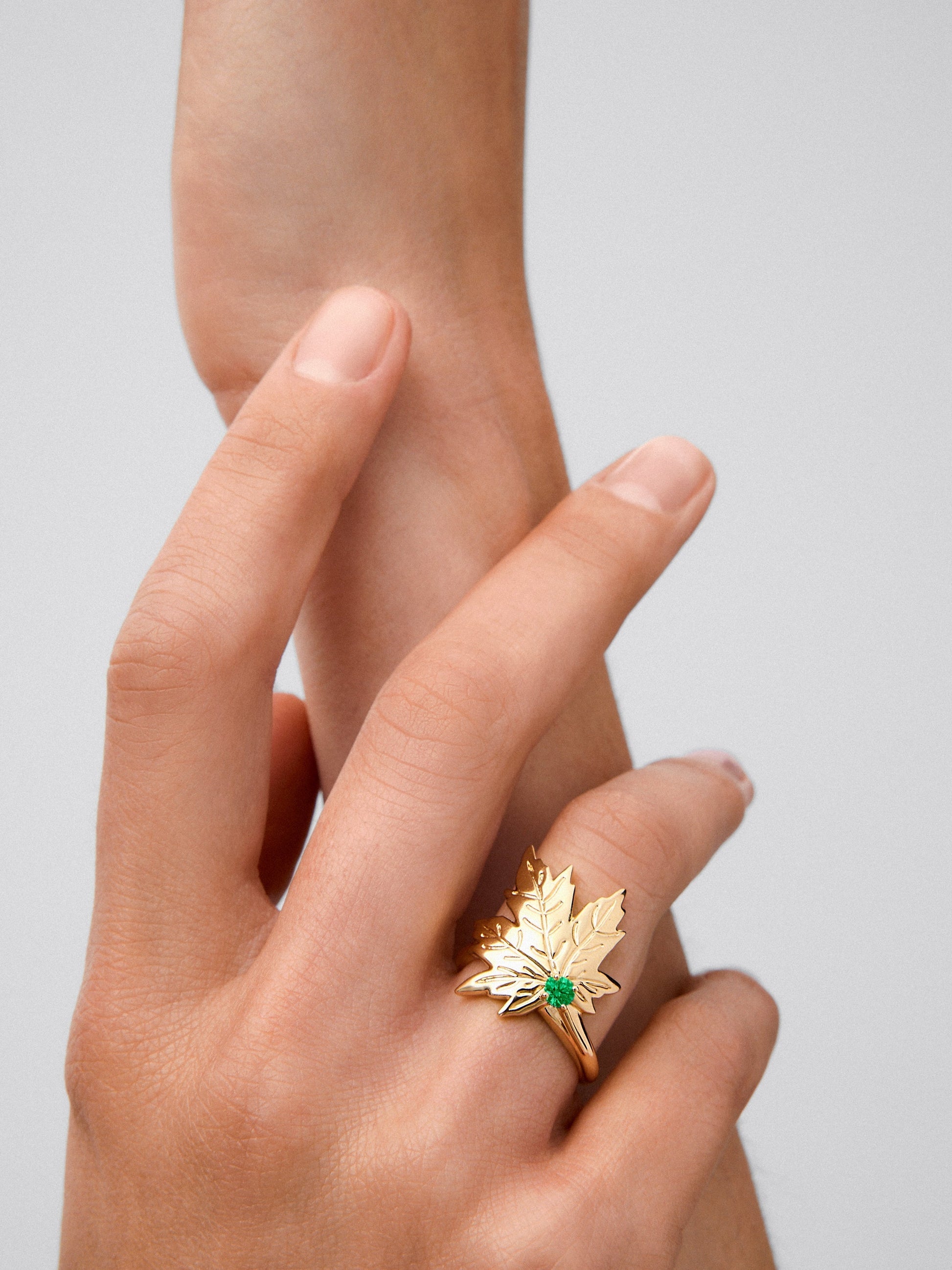 Anillo de oro amarillo de 18K con esmeralda central en talla brillante de 0,19 cts y forma de hoja de arce
