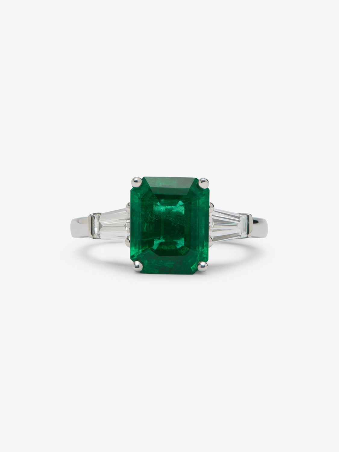 Anillo tresillo de oro blanco de 18K con esmeralda verde en talla octogonal de 3,6 cts y 2 diamantes en talla trapecio con un total de 0,68 cts