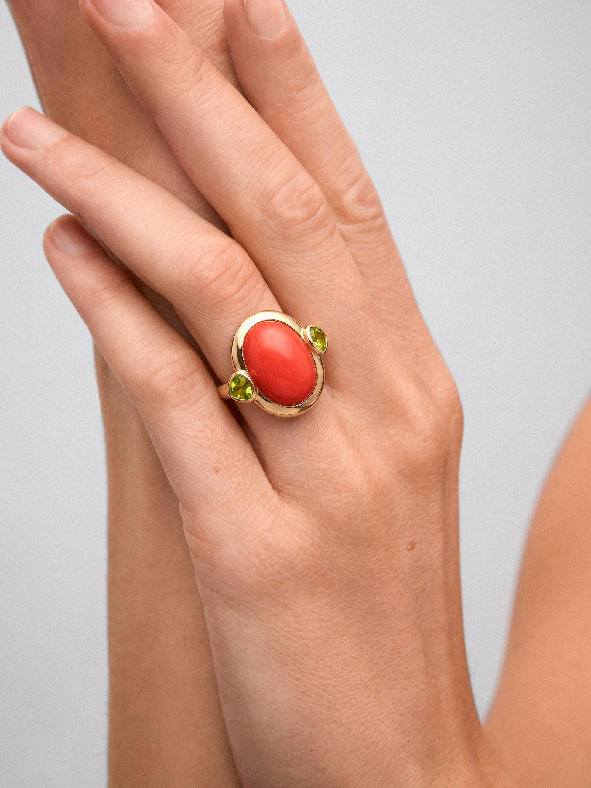 Anillo de oro amarillo de 18K con coral en talla oval y 2 peridotos verdes en talla pera