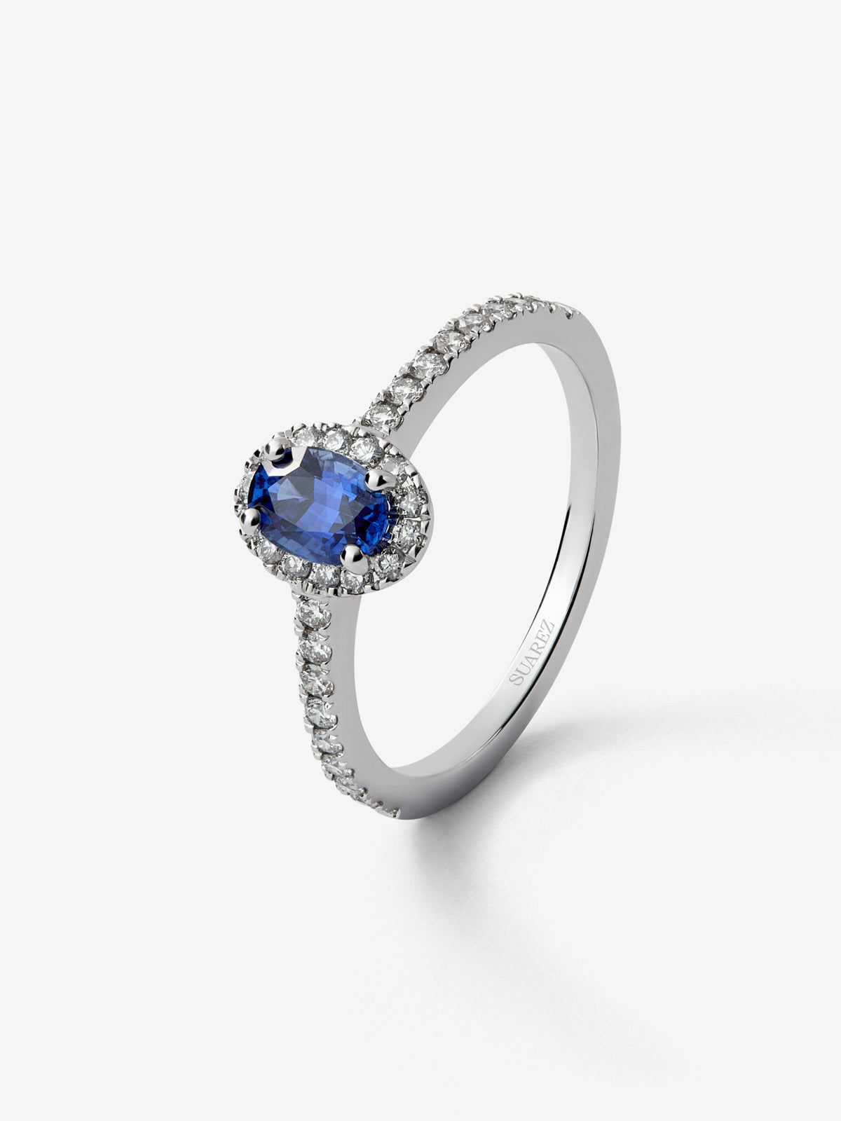 Anillo de oro blanco de 18K con zafiro azul en talla oval de 0,91 cts y orla de diamantes en talla brillante con un total de 0,37 cts