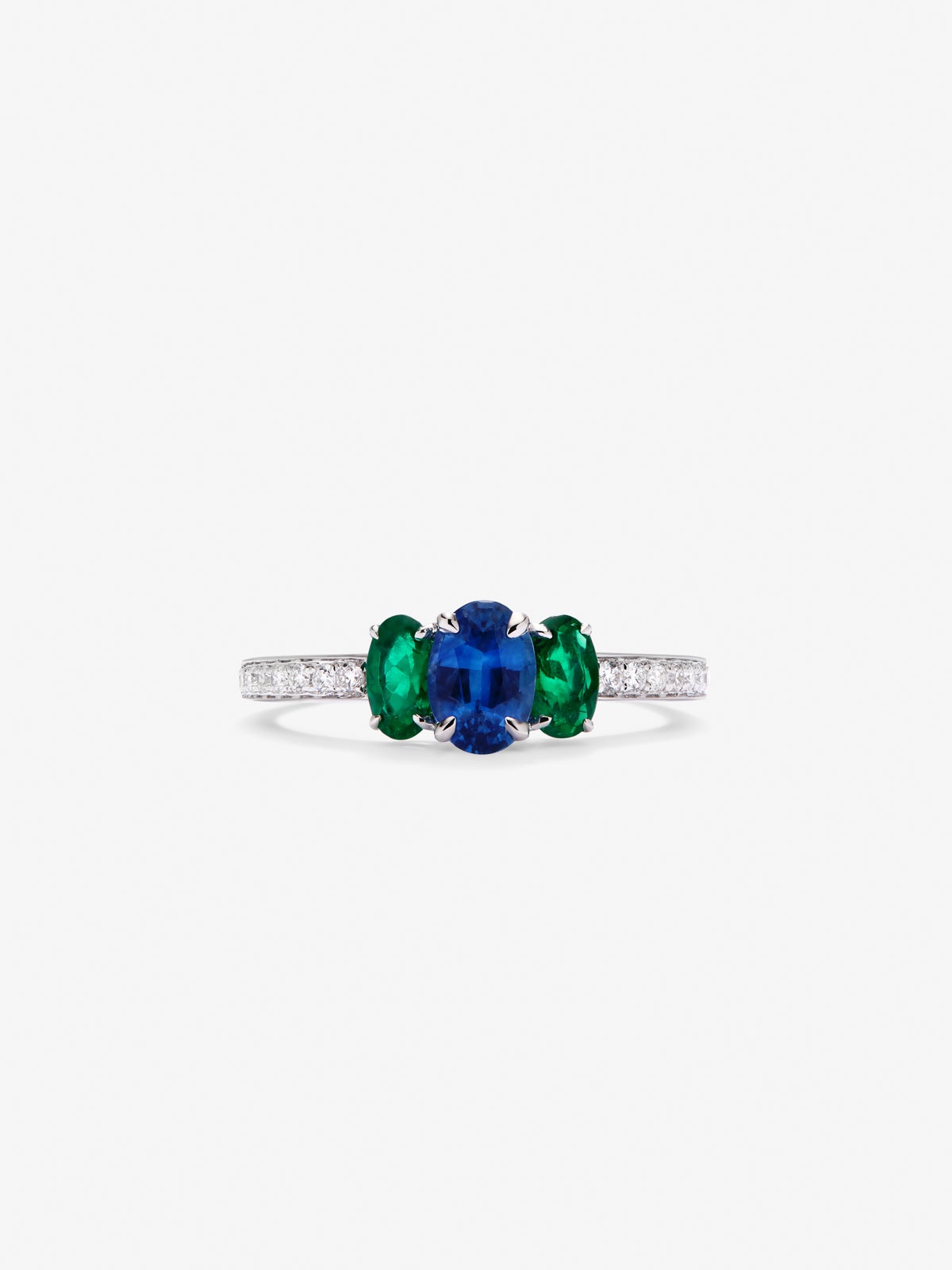 Anillo tresillo de oro blanco de 18K con zafiro azul en talla oval de 0,7 cts, esmeraldas verdes en talla oval de 0,41 cts y diamantes blancos en talla brillante de 0,115 cts