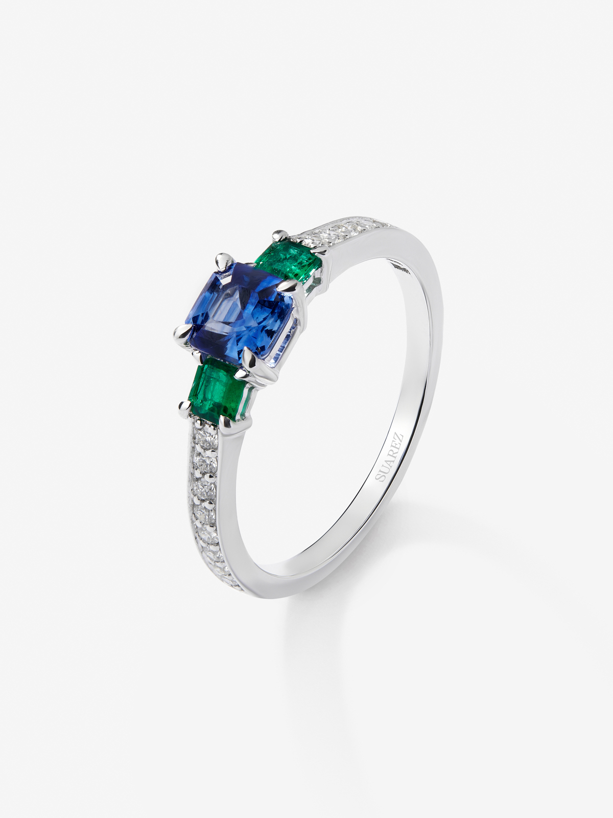 Anillo tresillo de oro blanco de 18K con zafiro azul en talla esmeralda de 0,71 cts, esmeraldas verdes en talla octogonal de 0,21 cts y diamantes blancos en talla brillante de 0,02 cts