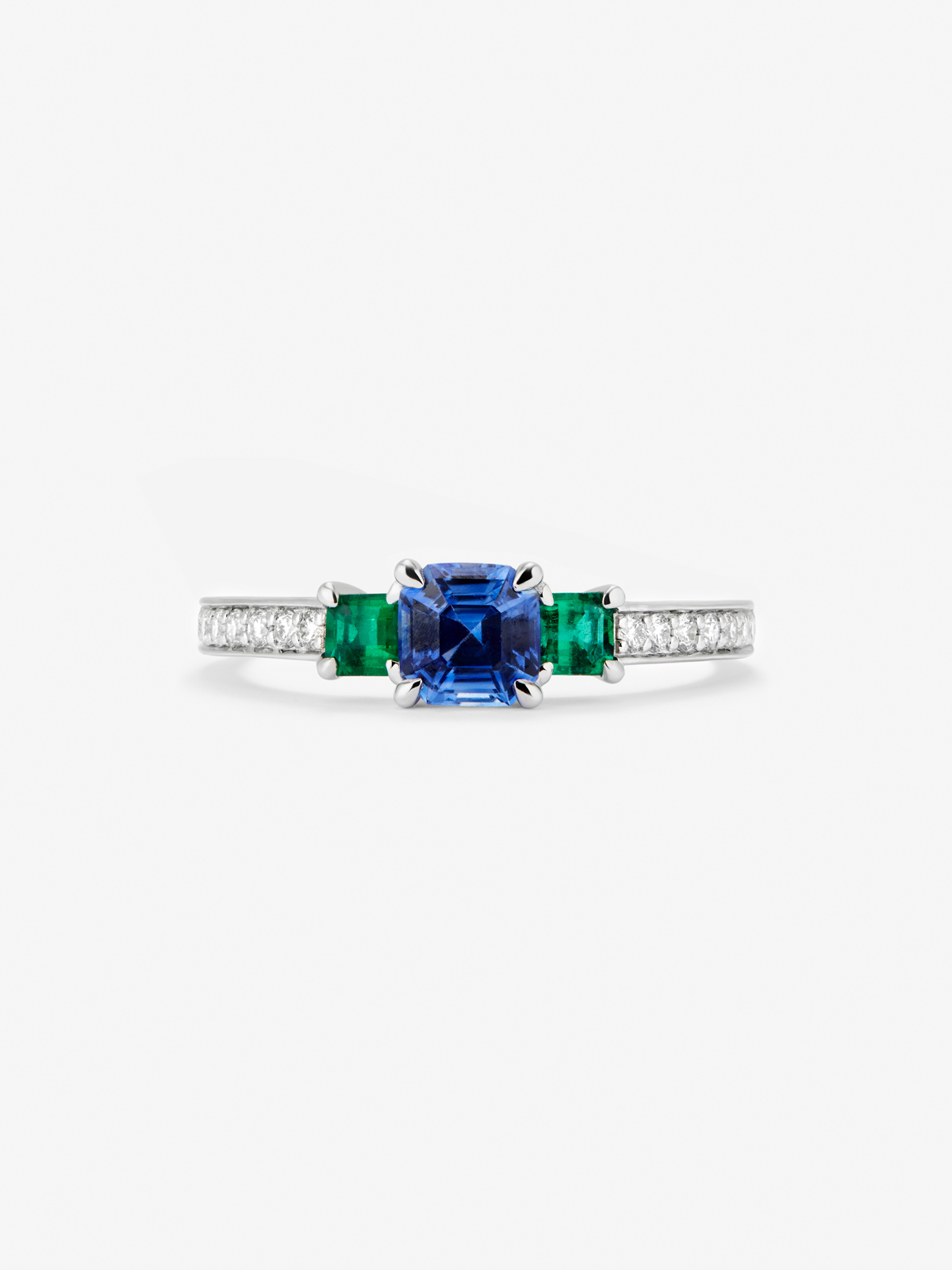 Anillo tresillo de oro blanco de 18K con zafiro azul en talla esmeralda de 0,71 cts, esmeraldas verdes en talla octogonal de 0,21 cts y diamantes blancos en talla brillante de 0,02 cts