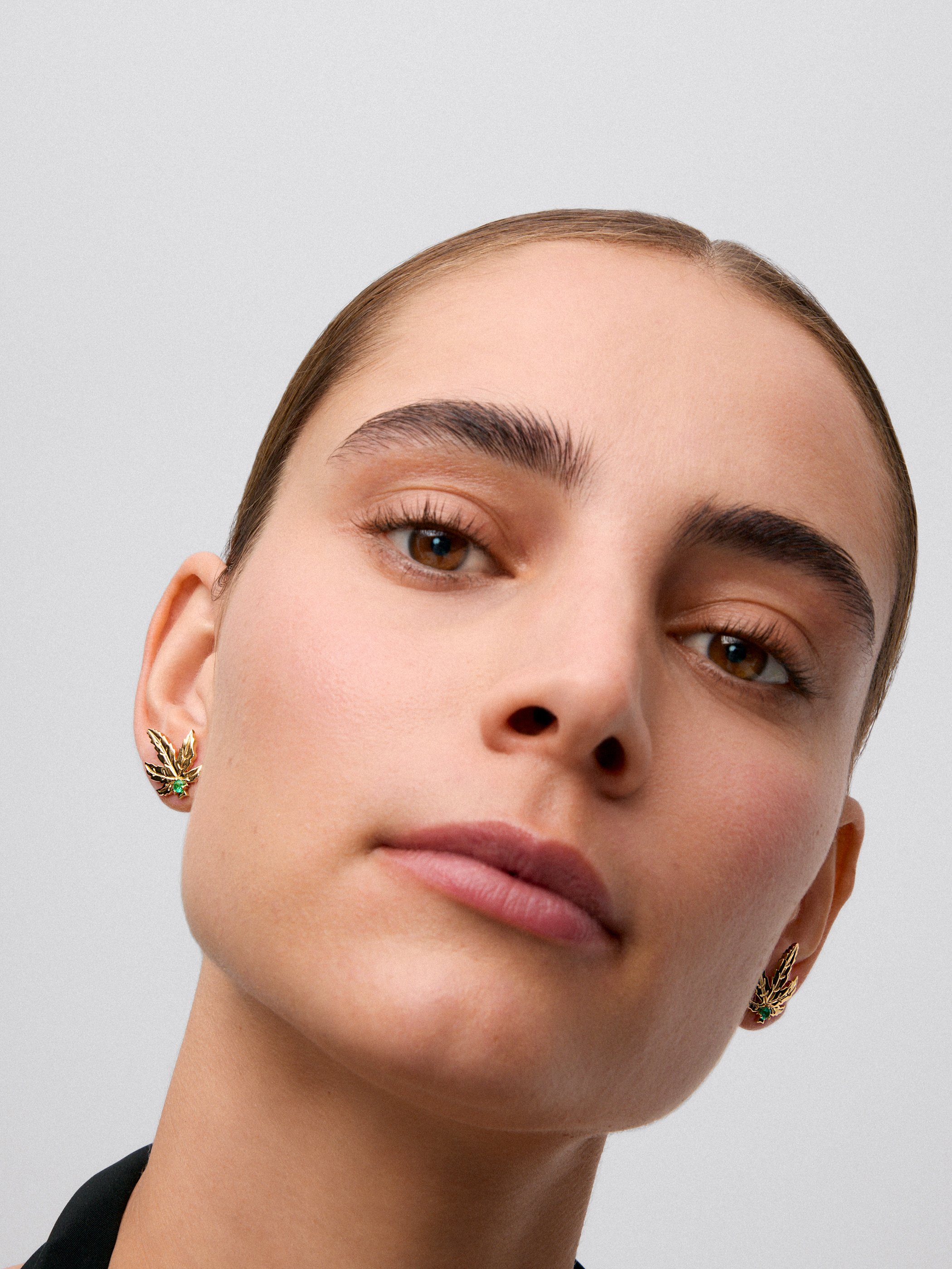 Pendientes de oro amarillo de 18K con 2 esmeraldas centrales con un total de 0,15 cts y forma de hoja de arce