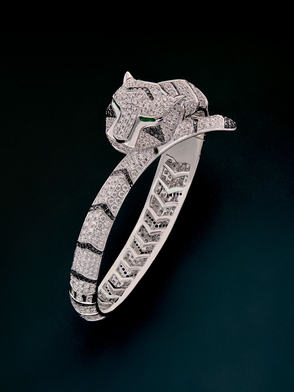 Rigid 18K white gold bracelet with brilliant-cut white diamonds of 8.17 cts and black diamonds of 1.49 cts, and trapezoid-cut emeralds of 0.13 cts in the shape of a tiger