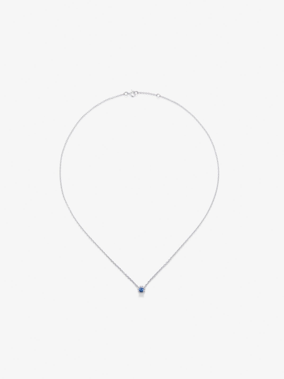 Colgante de oro blanco de 18K con zafiro azul en talla brillante de 0,23 cts y orla de 10 diamantes en talla brillante con un total de 0,07 cts