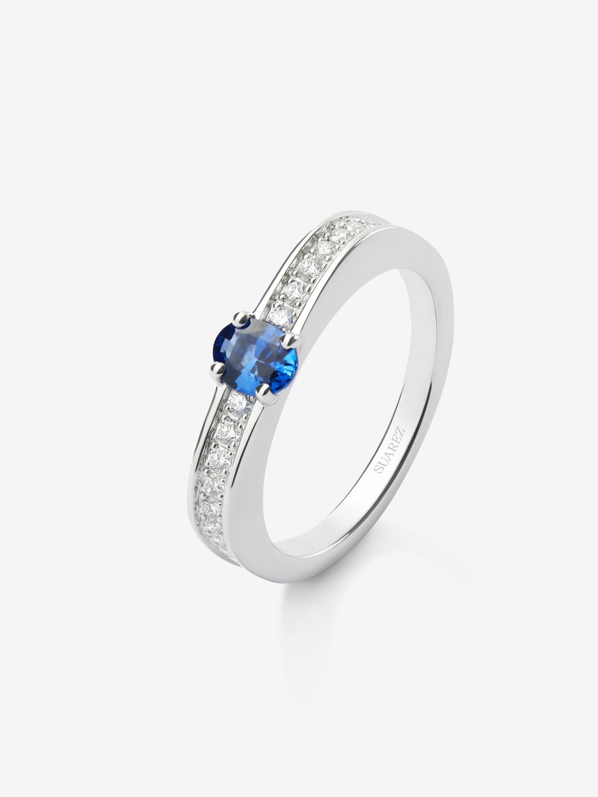 Anillo de oro blanco de 18K con zafiro azul en talla oval de 0,47 cts y 22 diamantes en talla brillante con un total de 0,16 cts